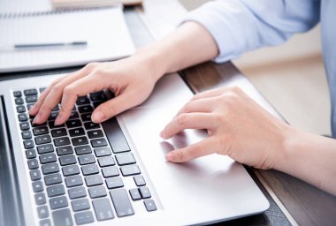 İş konsepti. Ofis masasında kahve ile bilgisayarda yazarak mavi gömlekli kadın, arka aydınlatma, güneş parlama etkisi, yakın, yan görünüm, kopyalama alanı