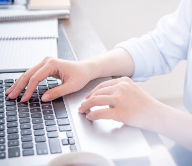 İş konsepti. Ofis masasında kahve ile bilgisayarda yazarak mavi gömlekli kadın, arka aydınlatma, güneş parlama etkisi, yakın, yan görünüm, kopyalama alanı
