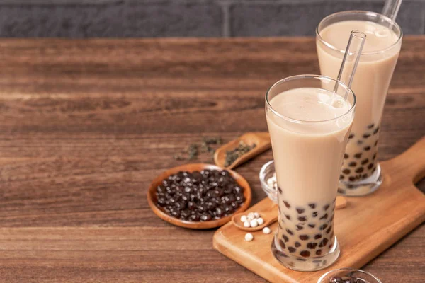 Boisson populaire à Taiwan - Thé au lait à bulles avec boule de perles de tapioca en verre à boire et paille, fond en brique grise de table en bois, gros plan, espace de copie — Photo