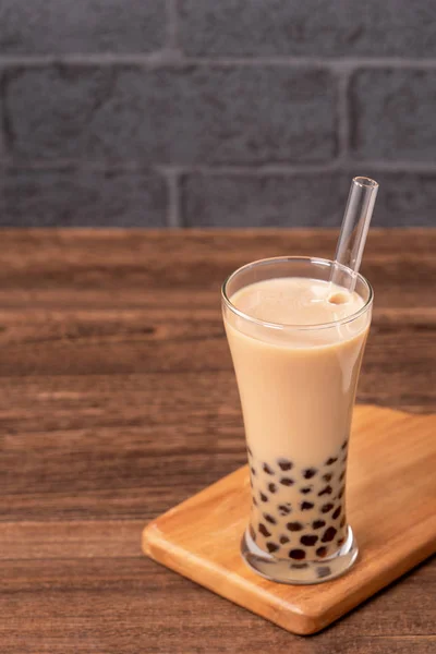 Beliebtes Taiwan-Getränk - Bubble Milch Tea mit Tapioka-Perlenkugel in Trinkglas und Stroh, Holztisch grauer Backsteinhintergrund, Nahaufnahme, Kopierraum — Stockfoto