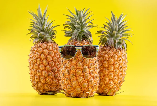 Kreativ ananas tittar upp med solglasögon och skal isolerade på gul bakgrund, sommarsemester strand idé designmönster, kopiera utrymme närbild — Stockfoto