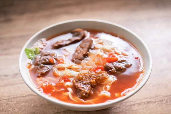 明るい木製のテーブルの上にボウルにトマトソーススープと牛肉ラーメンの食事, 台湾の有名な中華料理, クローズアップ, トップビュー, コピースペース — ストック写真