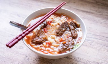 Parlak ahşap masada kase domates sosu suyu ile Sığır şehriye ramen yemek, Tayvan ünlü Çin tarzı gıda, yakın, üst görünümü, kopya alanı