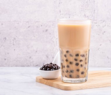 Popular Taiwan drink - Bubble milk tea with tapioca pearl ball in drinking glass on marble white table wooden tray background, close up, copy space clipart