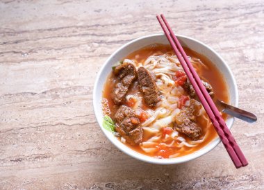 Parlak ahşap masada kase domates sosu suyu ile Sığır şehriye ramen yemek, Tayvan ünlü Çin tarzı gıda, yakın, üst görünümü, kopya alanı