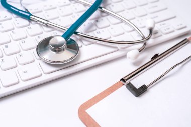 Beyaz masa arka planı üzerinde bilgisayar klavyesi üzerinde Mavi stetoskop. Online tıbbi bilgi tedavi teknolojisi kavramı, yakın çekim, makro, kopyalama alanı