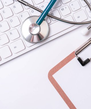 Beyaz masa arka planı üzerinde klavye üzerinde Stetoskop. Online tıbbi bilgi tedavi teknolojisi ofis konsepti, üst görünüm, düz yatıyordu, kopyalama alanı