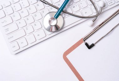 Beyaz masa arka planı üzerinde klavye üzerinde Stetoskop. Online tıbbi bilgi tedavi teknolojisi ofis konsepti, üst görünüm, düz yatıyordu, kopyalama alanı