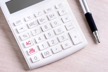 Parlak ahşap masa üzerinde beyaz hesap makinesi ve kalem, analitik ve finansal kar istatistikleri, yatırım riski kavramı, kopya alanı, üst görünüm düz yatıyordu