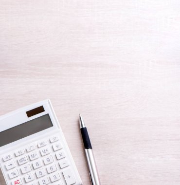 Parlak ahşap masa üzerinde beyaz hesap makinesi ve kalem, analitik ve finansal kar istatistikleri, yatırım riski kavramı, kopya alanı, üst görünüm düz yatıyordu