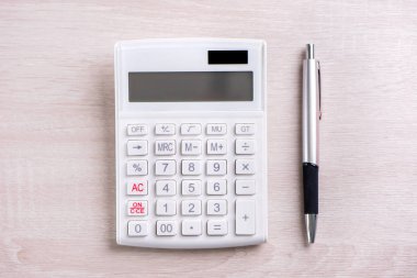 Parlak ahşap masa üzerinde beyaz hesap makinesi ve kalem, analitik ve finansal kar istatistikleri, yatırım riski kavramı, kopya alanı, üst görünüm düz yatıyordu