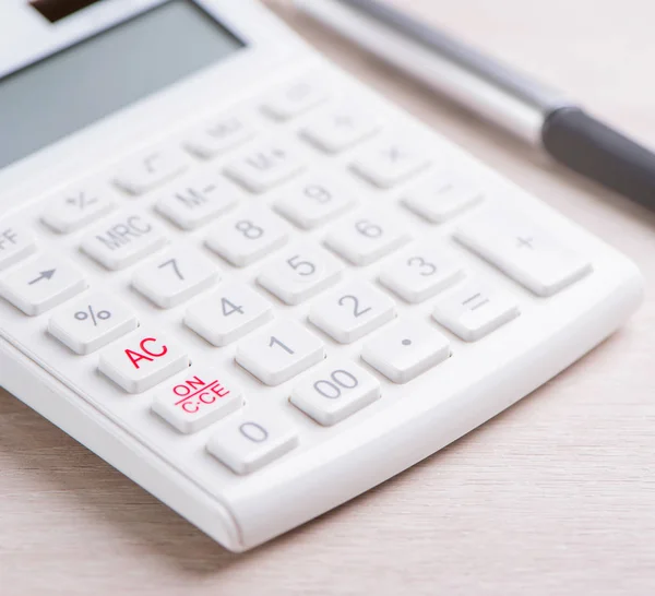 Белый калькулятор и ручка на светлом деревянном столе, аналитика и статистика финансовой прибыли, концепция инвестиционных рисков, копировальная площадка, вид сверху квартиры — стоковое фото
