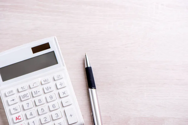 Calculadora branca e caneta em mesa de madeira brilhante, análise e estatísticas de lucro financeiro, conceito de risco de investimento, espaço de cópia, vista superior flat lay — Fotografia de Stock