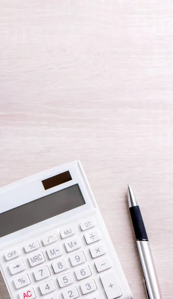 Parlak ahşap masa üzerinde beyaz hesap makinesi ve kalem, analitik ve finansal kar istatistikleri, yatırım riski kavramı, kopya alanı, üst görünüm düz yatıyordu