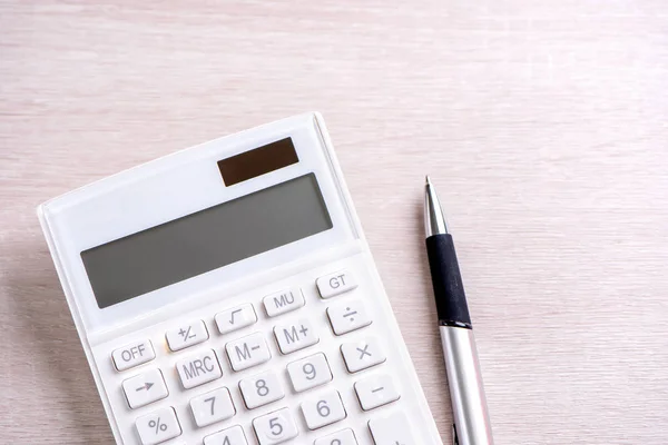 Calculadora branca e caneta em mesa de madeira brilhante, análise e estatísticas de lucro financeiro, conceito de risco de investimento, espaço de cópia, vista superior flat lay — Fotografia de Stock