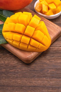 Ahşap kesme tahtası ve rustik ahşap arka plan taze doğranmış mango küpleri. Tropikal yaz meyve konsepti, yakın çekim, makro, kopyalama alanı. 