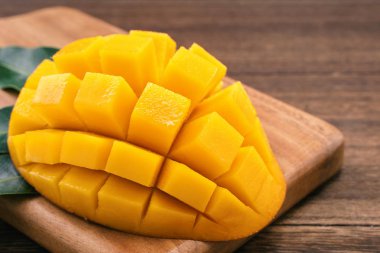 Ahşap kesme tahtası ve rustik ahşap arka plan taze doğranmış mango küpleri. Tropikal yaz meyve konsepti, yakın çekim, makro, kopyalama alanı. 