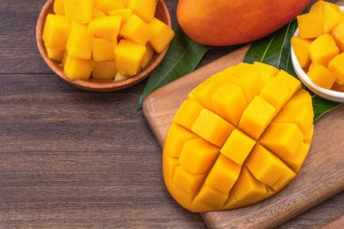 Ahşap kesme tahtası ve rustik ahşap arka plan taze doğranmış mango küpleri. Tropikal yaz meyve konsepti, yakın çekim, makro, kopyalama alanı. 