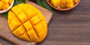 Ahşap kesme tahtası ve rustik ahşap arka plan taze doğranmış mango küpleri. Tropikal yaz meyve konsepti, yakın çekim, makro, kopyalama alanı. 