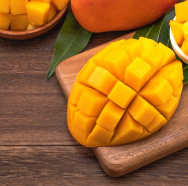 Ahşap kesme tahtası ve rustik ahşap arka plan taze doğranmış mango küpleri. Tropikal yaz meyve konsepti, yakın çekim, makro, kopyalama alanı. 