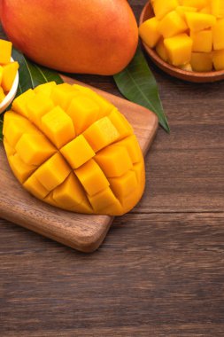 Ahşap kesme tahtası ve rustik ahşap arka plan taze doğranmış mango küpleri. Tropikal yaz meyve konsepti, yakın çekim, makro, kopyalama alanı. 