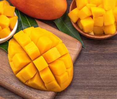Ahşap kesme tahtası ve rustik ahşap arka plan taze doğranmış mango küpleri. Tropikal yaz meyve konsepti, yakın çekim, makro, kopyalama alanı. 