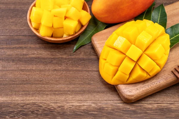 Färska hackade Mango kuber på trä skärbräda och rustik timmer bakgrund. Tropiska sommarfrukt koncept, närbild, makro, kopiera utrymme. — Stockfoto