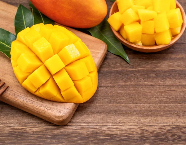 Färska hackade Mango kuber på trä skärbräda och rustik timmer bakgrund. Tropiska sommarfrukt koncept, närbild, makro, kopiera utrymme. — Stockfoto