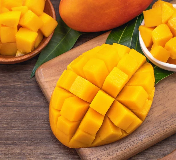 Fresh chopped mango cubes on wooden cutting board and rustic timber background. Tropical summer fruit concept, close up, macro, copy space. — Stock Photo, Image