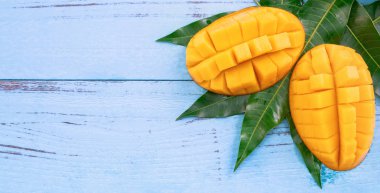Parlak mavi renkli ahşap arka plan üzerinde yeşil yaprakları ile Taze doğranmış mango. Yukarıda üst görünümü, düz yatıyordu, kopyalama alanı, yakın. Tropikal meyve konsepti.
