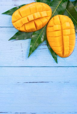 Parlak mavi renkli ahşap arka plan üzerinde yeşil yaprakları ile Taze doğranmış mango. Yukarıda üst görünümü, düz yatıyordu, kopyalama alanı, yakın. Tropikal meyve konsepti.