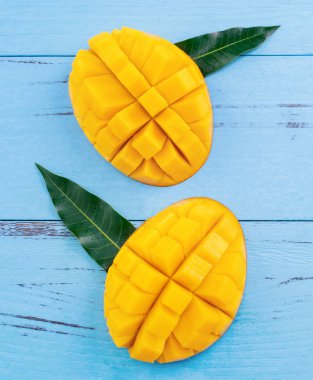 Parlak mavi renkli ahşap arka plan üzerinde yeşil yaprakları ile Taze doğranmış mango. Yukarıda üst görünümü, düz yatıyordu, kopyalama alanı, yakın. Tropikal meyve konsepti.