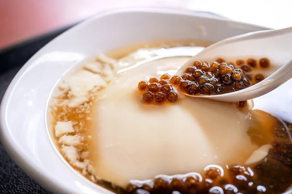 Popular Taiwan gourmet - Dessert of tapioca pearl ball (bubble) mixed bean curd tofu pudding (douhua, dou hua) in white bowl, close up, lifestyle