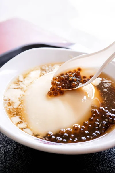 Popular Taiwan gourmet - Dessert of tapioca pearl ball (bubble) mixed bean curd tofu pudding (douhua, dou hua) in white bowl, close up, lifestyle