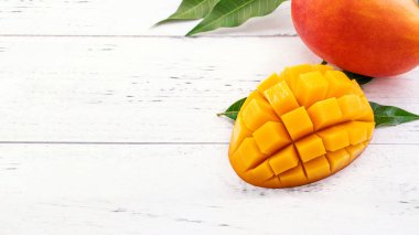 Parlak beyaz renkli ahşap arka plan üzerinde yeşil yaprakları ile güzel doğranmış mango. Yukarıda üst görünümü, düz yatıyordu, kopyalama alanı, yakın. Tropikal meyve konsepti.