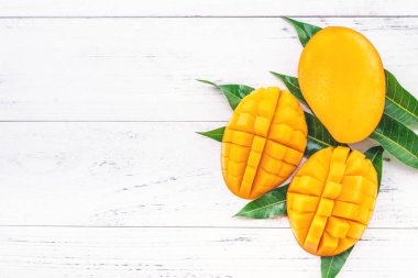 Parlak beyaz renkli ahşap arka plan üzerinde yeşil yaprakları ile güzel doğranmış mango. Yukarıda üst görünümü, düz yatıyordu, kopyalama alanı, yakın. Tropikal meyve konsepti.