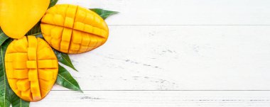 Parlak beyaz renkli ahşap arka plan üzerinde yeşil yaprakları ile güzel doğranmış mango. Yukarıda üst görünümü, düz yatıyordu, kopyalama alanı, yakın. Tropikal meyve konsepti.