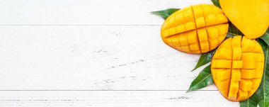 Parlak beyaz renkli ahşap arka plan üzerinde yeşil yaprakları ile güzel doğranmış mango. Yukarıda üst görünümü, düz yatıyordu, kopyalama alanı, yakın. Tropikal meyve konsepti.