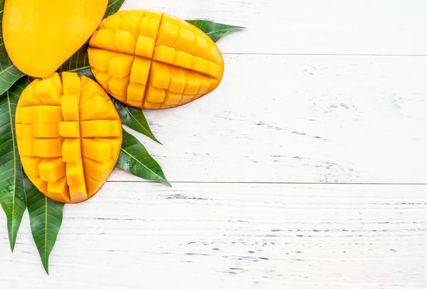 Vacker hackad Mango med gröna blad på ljust vit färg timmer bakgrund. Ovanför ovanifrån, platt Lay, kopiera utrymme, närbild. Tropiska frukter Concept. — Stockfoto