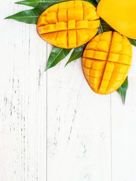 Vacker hackad Mango med gröna blad på ljust vit färg timmer bakgrund. Ovanför ovanifrån, platt Lay, kopiera utrymme, närbild. Tropiska frukter Concept. — Stockfoto