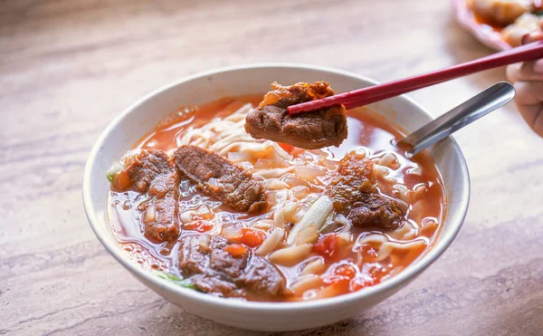牛肉麺 - 明るい木製のテーブルの上にボウルにトマトソーススープと台湾ラーメンの食事, 有名な中華風の食べ物, クローズアップ, トップビュー, コピースペース — ストック写真