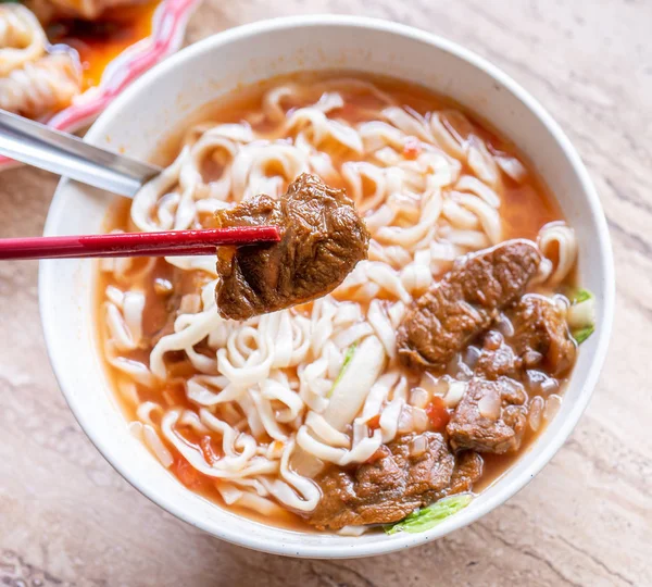 牛肉麺 - 明るい木製のテーブルの上にボウルにトマトソーススープと台湾ラーメンの食事, 有名な中華風の食べ物, クローズアップ, トップビュー, コピースペース — ストック写真