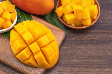 Taze Mango - Sulu ahşap kesme tahtası ve rustik ahşap arka plan üzerinde mango küpleri doğranmış. Tropikal yaz konsepti. Yakın çekim, makro, kopyalama alanı. 