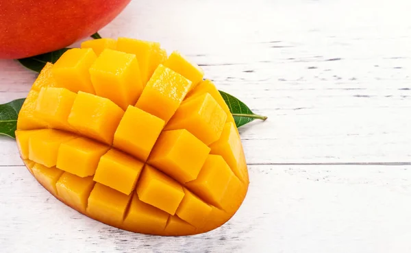 Vackra hackade Mango bitar med gröna blad på ljust vit färg timmer bakgrund. Kopiera utrymme, närbild, makro. Tropiska frukter Concept. — Stockfoto