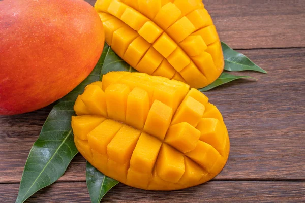 Mango fresco - bel frutto tritato con foglie verdi su sfondo di legno scuro. Concetto di progettazione tropicale della frutta. Piatto. Vista dall'alto. Copia spazio . — Foto Stock