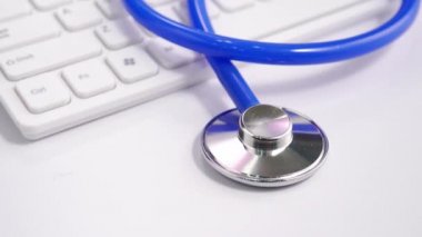 Medical Concept - Beyaz bilgisayar klavyesi üzerinde mavi stetoskop ile Doktor ofisi çalışma masası. Kamyon sağ, yakın çekim, makro çekim.