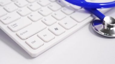 Medical Concept - Beyaz bilgisayar klavyesi üzerinde mavi stetoskop ile Doktor ofisi çalışma masası. Kamyon sağ, yakın çekim, makro çekim.