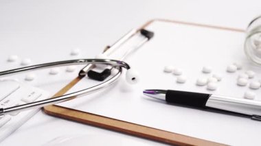 Tıbbi Konsept - Beyaz bilgisayar klavyesi ve yanında ilaçlar üzerinde mavi stetoskop ile Doktor ofisi çalışma masası. Kamyon sol, yakın çekim, makro.