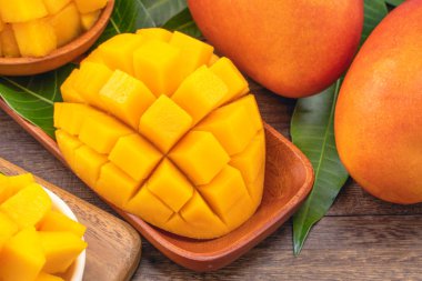 Ahşap kesme tahtası ve rustik ahşap arka plan taze doğranmış mango küpleri. Tropikal yaz meyve konsepti, yakın çekim, makro, kopyalama alanı.