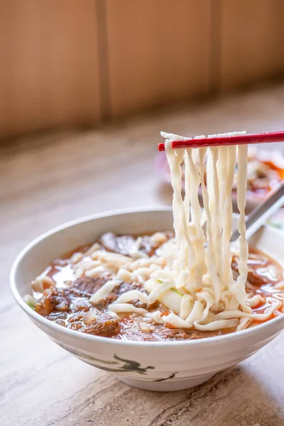牛肉麺 - 明るい木製のテーブルの上にボウルにトマトソーススープと台湾ラーメンの食事, 有名な中華風の食べ物, クローズアップ, トップビュー, コピースペース — ストック写真